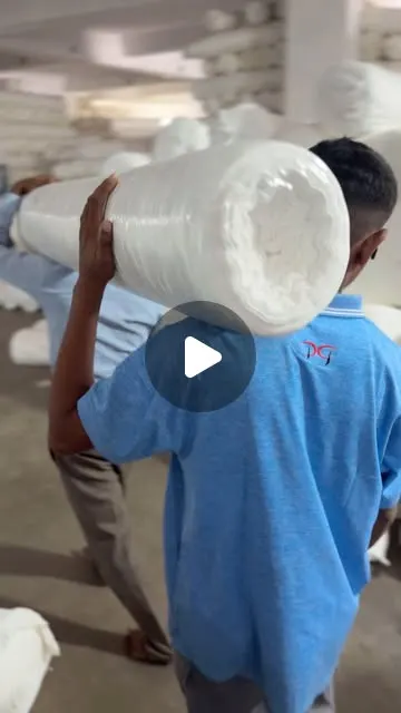 Reel cover: a DG Knitting worker carrying a fabric roll on the mill floor in Surat